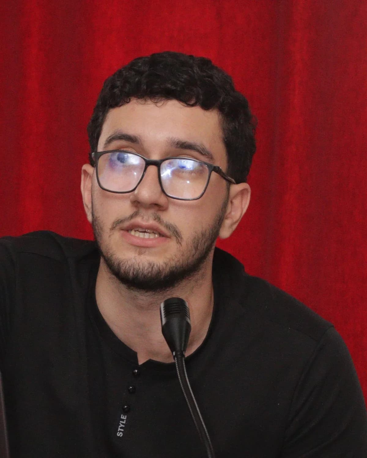Massinissa Mouhoub speaking into a microphone at a presentation